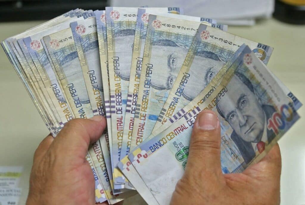 manos con billetes de cien soles peruanos